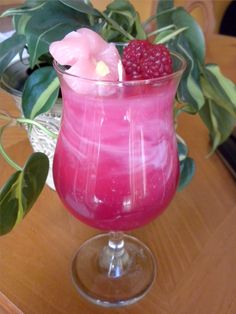 a pink drink with raspberries in it on a table