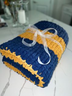 a blue and yellow towel with a bow on it sitting on a counter top next to a glass vase