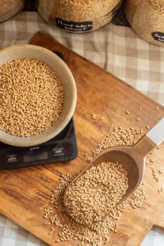 a wooden cutting board topped with lots of brown grains next to a measuring cup and spoon