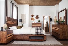 a bed room with a neatly made bed and wooden furniture on top of carpeted flooring