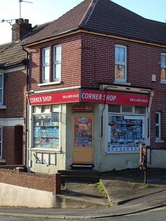 an old brick building with a corner shop on the front and side walk up to it