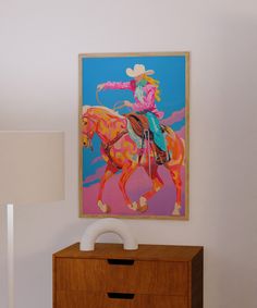 a painting hangs on the wall next to a dresser with a lamp in front of it