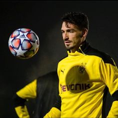 a man in yellow and black uniform holding a soccer ball with his right arm out