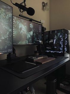 three computer monitors sitting on top of a desk next to a microphone and headphones