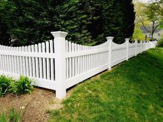 a white picket fence in front of some trees