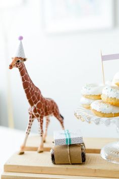 a giraffe figurine standing next to a tray of donuts on a table