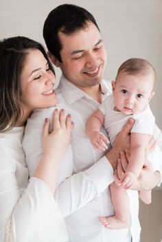 a man and woman holding a baby in their arms