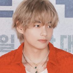 the young man is wearing a red jacket and necklace with green beads on it's neck