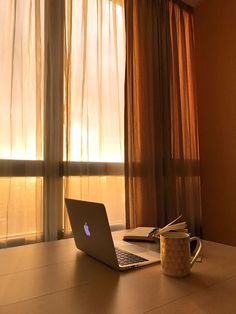 an open laptop computer sitting on top of a wooden table next to a cup of coffee