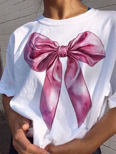 a woman wearing a white shirt with a pink bow on it