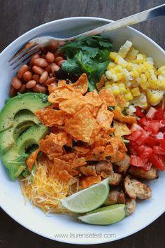 a white bowl filled with lots of different types of food on top of a wooden table