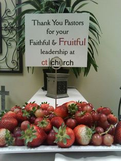 a table topped with lots of strawberries and other fruits next to a sign that says thank you pastor for your faithful & fruitful