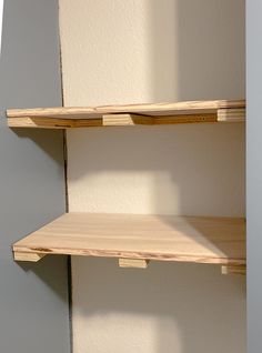 two empty wooden shelves against a white wall