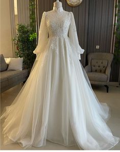 a white wedding dress on display in a room with a clock and chair behind it