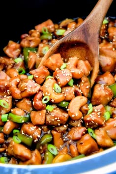 a wooden spoon in a blue bowl filled with chicken and broccoli stir fry