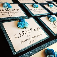 several cards with blue flowers on them sitting on a table next to some brooches