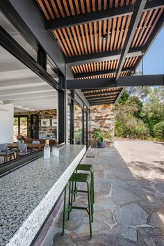 an outdoor patio with tables and chairs next to a large window that looks out onto the backyard