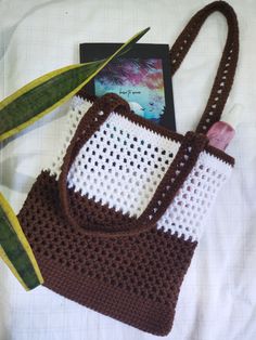 a crocheted purse with a book on it and a plant in the background