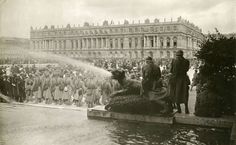 an old black and white photo of people standing in front of a building with water shooting out