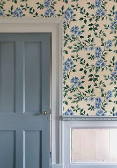 a blue door in front of a floral wallpaper