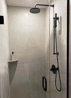 a walk in shower sitting next to a white sink under a faucet mounted on the side of a wall