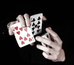 two hands holding playing cards in the dark