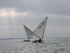 two sailboats in the water on a cloudy day