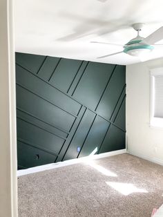 an empty room with a ceiling fan and green paneling on the wall behind it