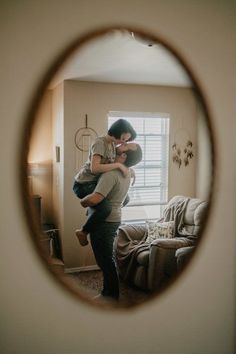 a man holding a woman in his arms looking through a magnifying glass to the living room