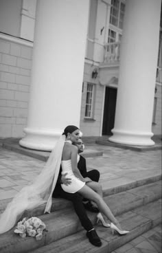 a bride and groom sitting on the steps in front of an old building with columns