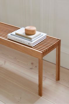 a wooden bench with two books on it and a bowl sitting on top of one