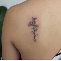 the back of a woman's shoulder with daisies tattoo on her left side