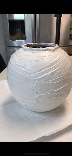 a large white vase sitting on top of a table covered in plastic wrapper next to a stove