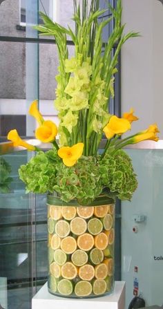 a vase filled with yellow flowers sitting on top of a white table next to a window