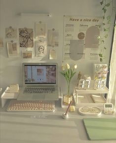 a laptop computer sitting on top of a desk next to a vase with flowers in it