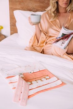 a woman sitting on a bed holding a cup of coffee