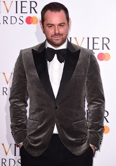 a man in a tuxedo and bow tie posing for the camera at an awards event