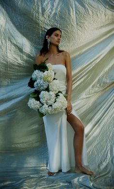 a woman in a white dress holding flowers