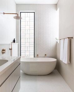 a bathroom with a tub, sink and mirror in it's center wall is shown