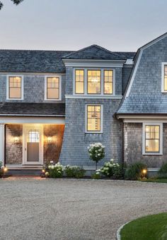 a large gray house with lots of windows and lights on it's front door