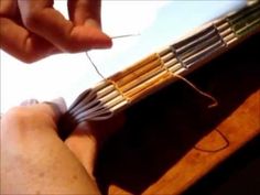 a person is holding an instrument in their left hand and threading the strings on it