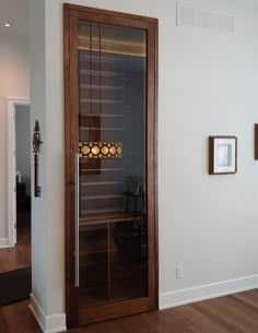 an empty room with a glass door and wood flooring, along with pictures on the wall