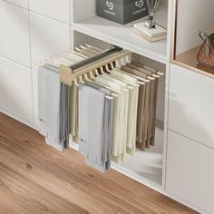 a white book shelf filled with books next to a vase and other items on top of a wooden floor