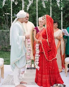 a man and woman standing next to each other in front of a wedding ceremony arch