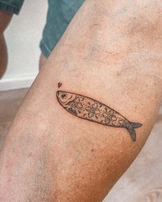 a small fish tattoo on the right leg, with flowers and hearts in the center