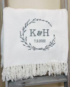 a white towel with the initials k and h on it sitting on top of a ladder