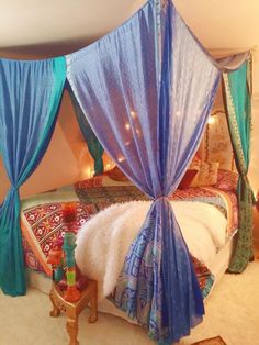 a canopy bed with blue drapes on it's sides and lights hanging from the ceiling