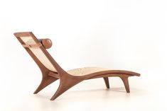 a wooden lounge chair sitting on top of a white floor