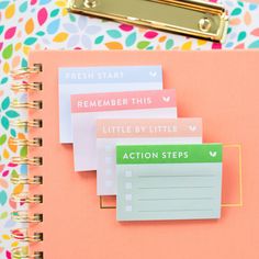 a pink notebook with stickers on it next to a clipboard and a gold binder