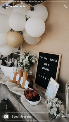 a table topped with lots of food and balloons hanging from the ceiling above it is a sign that says pop the bubbly she's getting a hubby